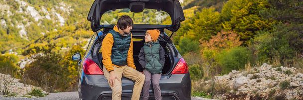 Dad and son are resting on the side of the road on a road trip. Road trip with children concept. BANNER, LONG FORMAT - Photo, Image