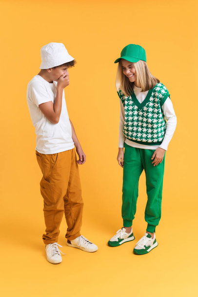 White girl and boy laughing while making fun together isolated over yellow background - Valokuva, kuva