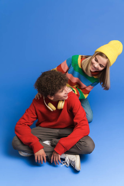 White girl and boy laughing and hugging while posing at camera isolated over blue background - Foto, immagini