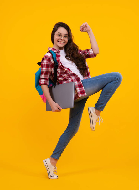 Back to school. Teenager schoolgirl hold notebook laptop. School children on isolated yellow studio background. Run and jump, jumping kid - Photo, image