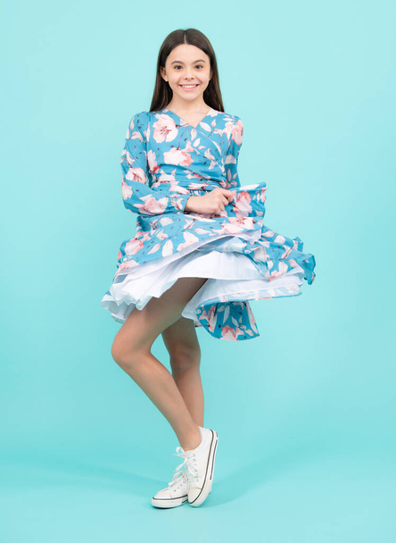Movement dress of young child teen girl. Happy teenager, positive and smiling emotions. Elegant teenager child girl in fashion summer dress. Girl dressed in cotton dress isolated on blue background - 写真・画像