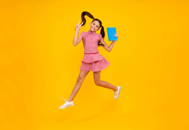 Teen girl pupil hold books, notebooks, isolated on yellow background, copy space. Back to school, teenage lifestyle, education and knowledge. Happy teenager, positive and smiling schoolgirl - Fotó, kép