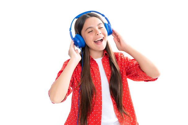 Teenager σε σύγχρονα ασύρματα ακουστικά απολαμβάνοντας μουσική τραγουδιού σε ακουστική εφαρμογή, ακούγοντας την αγαπημένη της μουσική πάνω από κίτρινο φόντο στούντιο - Φωτογραφία, εικόνα