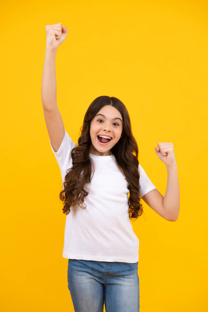 Amazed teenager. Excited teen girl. Teenager child overjoyed successful do winner gesture clench fist say yes isolated on yellow background studio - Photo, image