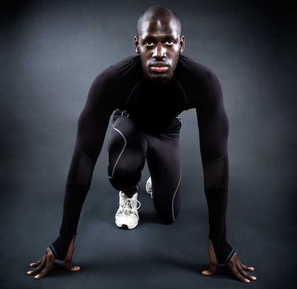 Athletic man running in black background. - Фото, изображение