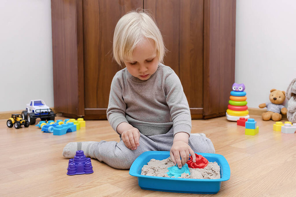 Cute little child boy playing at home in sensory box with kinetic sand.Development of fine motor skills. Early sensory education. Activities Montessori.art creativity, craft at daycare,kindergarten. - Foto, imagen