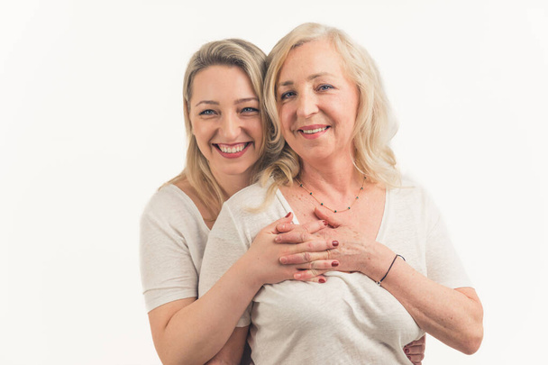 Two attractive women in their 40s hugging and looking at each other affectionately, holding hands, interlaced fingers. . High quality photo - Photo, image