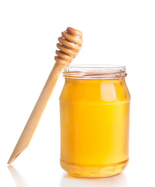 opened honey jar on white background near wooden honey dipper - Фото, изображение