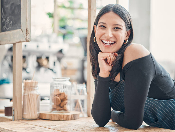 Portrait of one happy young hispanic waitress working in a store or cafe. Friendly woman and coffeeshop owner managing a successful restaurant startup. - 写真・画像