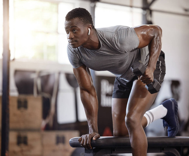 Serious african american athlete lifting dumbbell in tricep curl workout on bench in gym. Strong, fit, active black man training with weights in health and sport club. Weightlifting exercise routine. - Foto, Imagem
