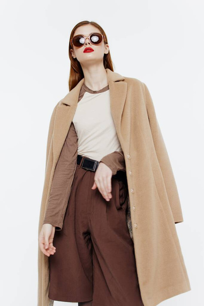 Un modelo femenino elegante brillante en un abrigo posa sobre un fondo blanco. Banner para diseñadores de moda, salas de exposición. Foto de alta calidad - Foto, Imagen