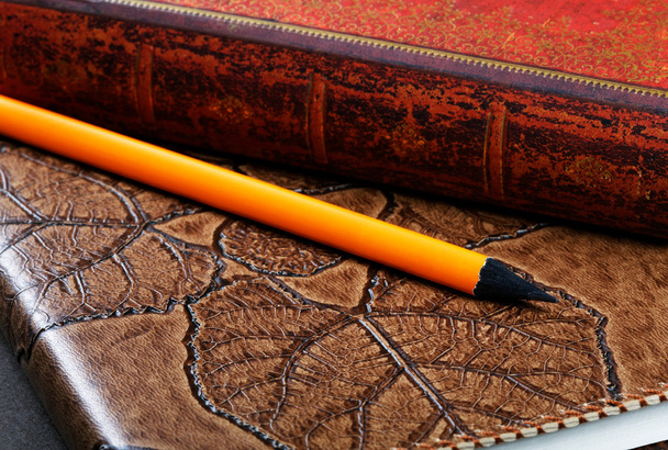 Pile of notebooks in leather covers and a pencil close up - 写真・画像
