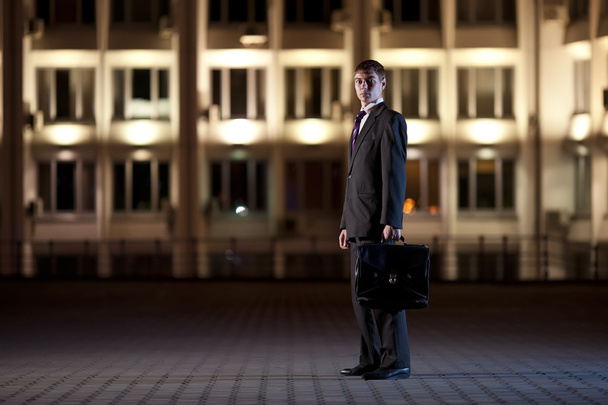 Handsome businessman with briefcase at night city in the backgro - Fotoğraf, Görsel