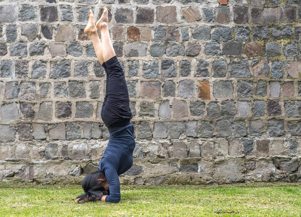 Young woman practicing headstand yoga in a park - Φωτογραφία, εικόνα