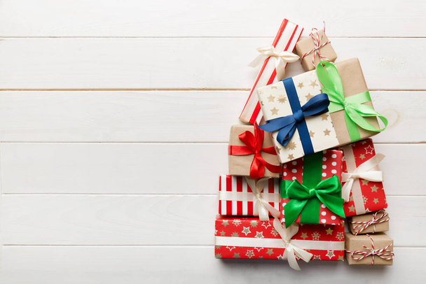 Renkli arka planda güzel paketlenmiş hediyelerden yapılmış Noel ağacı, yukarıdan görünüyor. Kopya alanı olan en küçük hediye kutusu konsepti. - Fotoğraf, Görsel