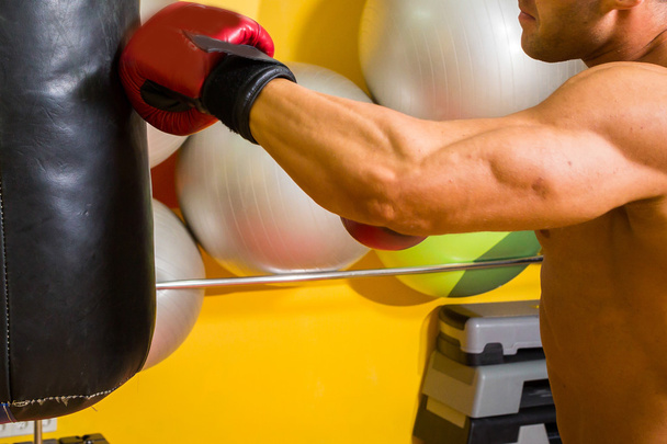 Мускулистый человек в боксёрских перчатках в спортзале
 - Фото, изображение