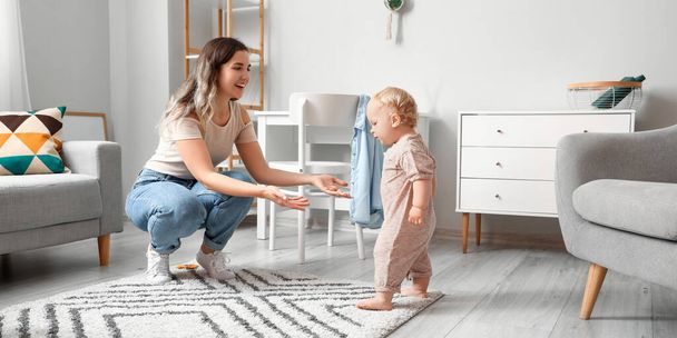 Mother teaching her cute baby to walk at home - Foto, Bild