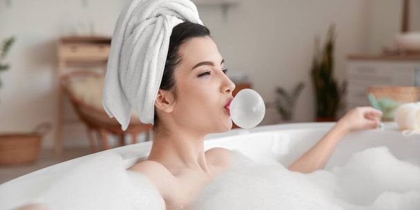Relaxed young woman with chewing gum taking bath at home - Foto, Imagen