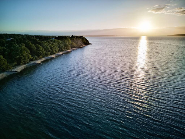 An aerial view from the sea of bright sun reflected in the water near the island - Fotografie, Obrázek