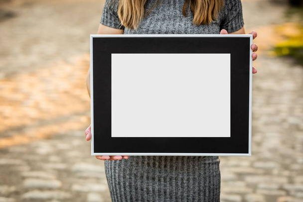 A girl was holding a gray frame with black passepartout without a picture - Fotoğraf, Görsel