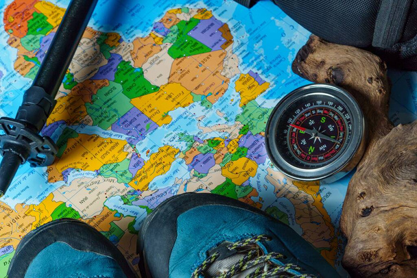 boots, backpack, walking stick and compass, trekking equipment on a map of the world. - Фото, зображення