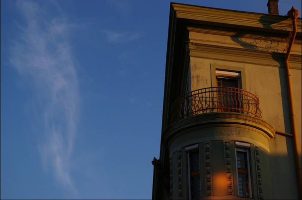 A low angle shot of corner of ornamental building with round balcony under blue sky - Valokuva, kuva