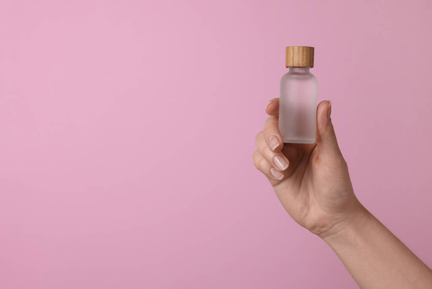 Woman holding bottle of cosmetic product on pink background, closeup. Space for text - Zdjęcie, obraz