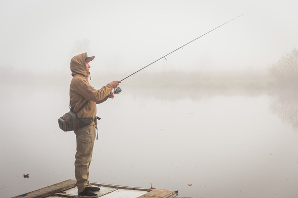 Fisherman with spinning on river bank - Zdjęcie, obraz