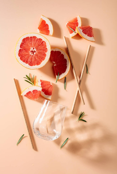 Grapefruit slices, rosemary, straws, and an empty glass. Top view. - Фото, зображення