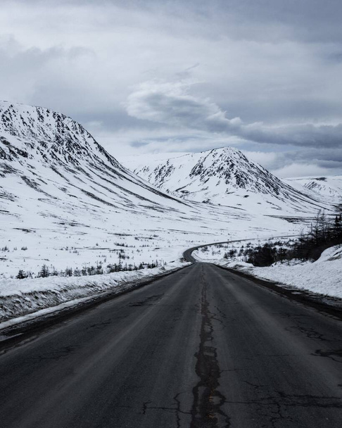 A vertical shot of a road against snowy mountains in New Brunswick, Canada - Φωτογραφία, εικόνα
