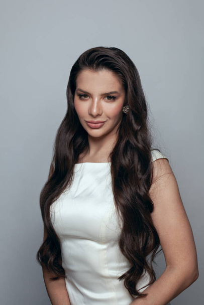 Elegant beautiful young woman fashion model brunette with long dark hairstyle standing on grey background - Valokuva, kuva