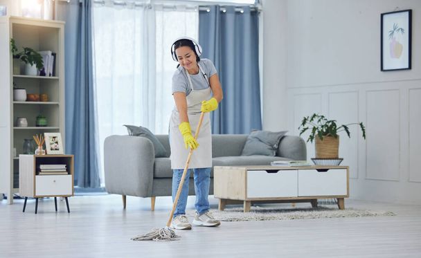 a young woman listening to music while mopping the floors at home. - 写真・画像