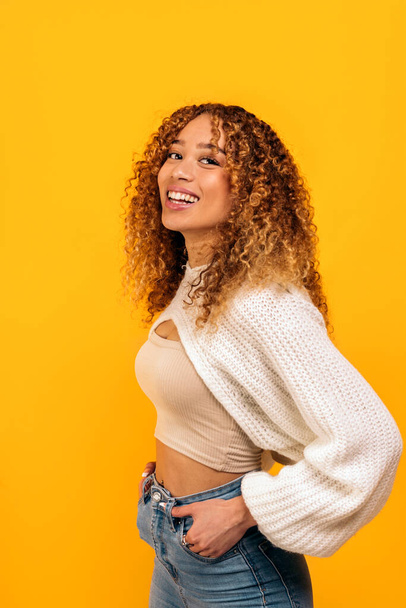 Stock photo of attractive young woman posing in studio shot against yellow background. - Φωτογραφία, εικόνα