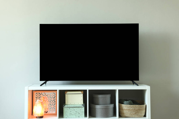 Modern TV and lamp on cabinet near white wall indoors. Interior design - Fotó, kép