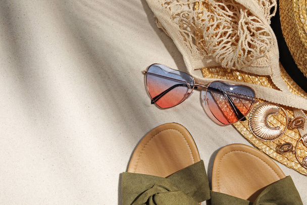 Flat lay composition with stylish sunglasses and other fashionable accessories on sand. Space for text - Φωτογραφία, εικόνα