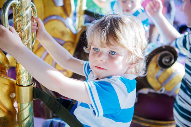 Little cute boy during carousel ride, enjoying and having fun - Photo, Image