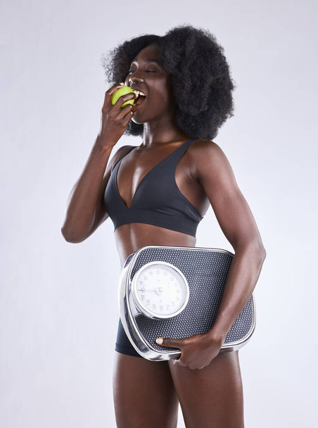 Студійний знімок жінки, що тримає яблуко і вагу
. - Фото, зображення