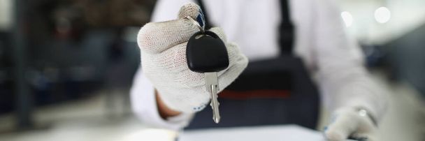 Close-up of service worker give keys from fixed automobile to owner and hold paper for sign. Car service, professional mechanic, garage, pit stop concept - Foto, immagini