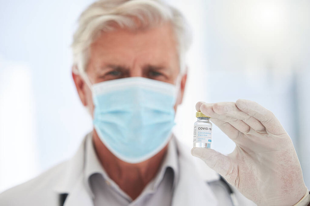 Yetişkin bir doktor bir hastanede aşı şişesi tutuyor.. - Fotoğraf, Görsel