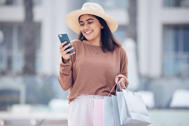 молодая женщина использует смартфон для отправки текста во время покупок. - Фото, изображение