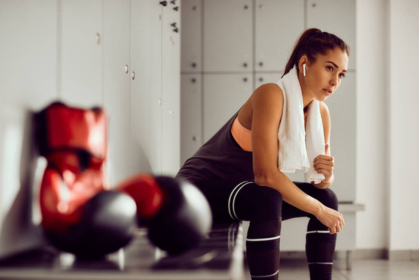 Young athletic woman sitting in locker room while preparing for boxing training in a gym. - Fotografie, Obrázek