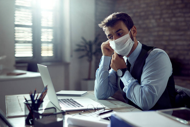 Young businessman wearing protective face mask while working in the office during coronavirus pandemic.  - Zdjęcie, obraz