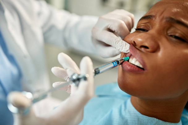 Close-up of black woman getting anesthetic during dental procedure at dentist's office.  - Zdjęcie, obraz