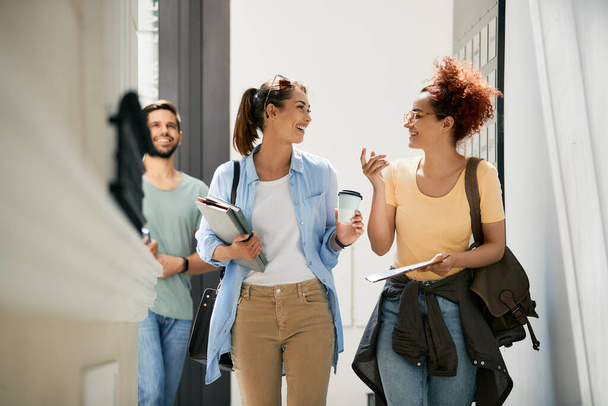 Щасливі студентки розмовляють під час прогулянки в університетському коридорі
.  - Фото, зображення