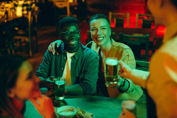 Genç, mutlu Afrikalı Amerikalı çift eğlenirken garson onlara barda bira servisi yapıyor..  - Fotoğraf, Görsel