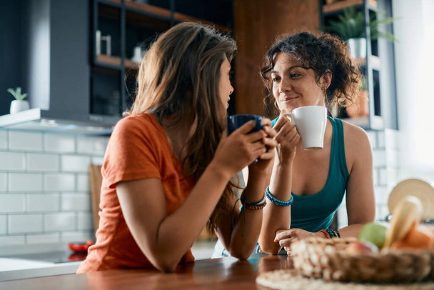 Young woman and her girlfriend enjoying in cup of coffee while talking at home. - Φωτογραφία, εικόνα