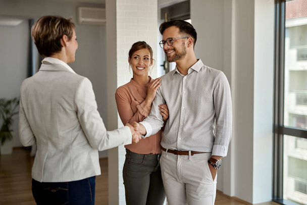 Happy couple buying a new home and handshaking with their real estate agent.  - Fotografie, Obrázek