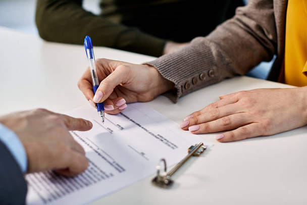 Close-up of woman signing agreement with insurance agent while buying new home with her husband.  - Foto, Bild
