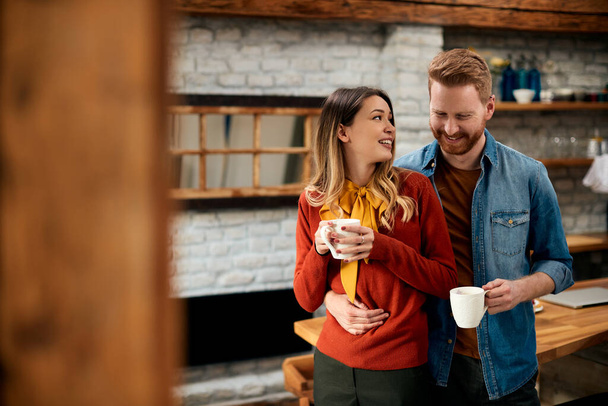 Young happy woman and her boyfriend communicating while enjoying in cup of coffee at home. - 写真・画像