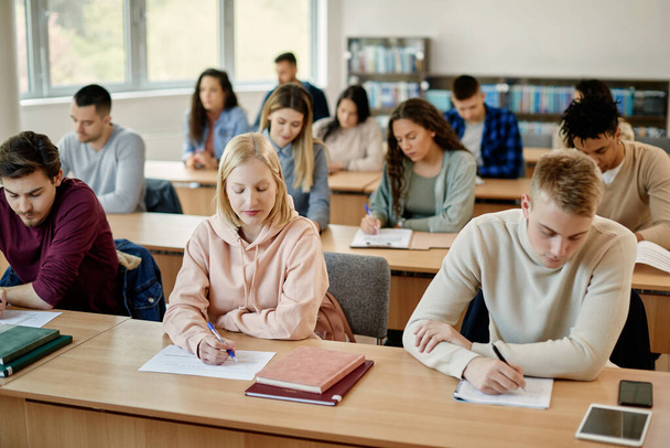 Студент коледжу та її однокласники пишуть іспит у класі
. - Фото, зображення